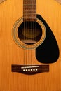 Vertical closeup of a yellow acoustic guitar under the lights