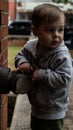 Vertical closeup of a young boy playing with water hookup on brick wall blurred background