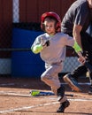 Vertical closeup of a young child playing baseball running to first base after a hit