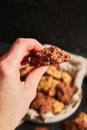 Vertical closuep shot of a hand holding a bitten oatmeal cookie