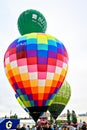 Vertical of the colorful air balloons landing on the ground in a crowdy park