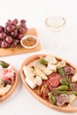 Vertical composition with antipasti plate - variety of cheeses, sausages served with glass of wine, sun dried tomatoes, olives