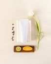 Natural cosmetic composition with cosmetic tube on a white towel with tulip, orange and laim