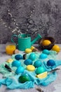 Vertical composition for Easter. Painted yellow, blue, green eggs on a napkin with macaroons and lemons on a light gray background Royalty Free Stock Photo