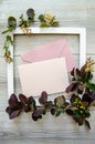 Vertical composition with flatlay with square white wooden frame and mockup and copyspace pastel pink envelopes