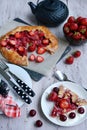 Vertical composition of homemade summer tea party. Strawberry pie, teapot, plates, knife, spoons and a bowl with fresh Royalty Free Stock Photo