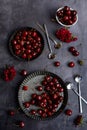 Vertical composition. Ripe cherries in metal bowls and flowers on a gray background. View from above