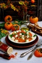 Vertical composition. Sweet salad of persimmons, arugula, cheese and walnuts on a light wooden background. Spicy