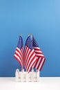 Vertical composition with three american flags on white table with blue wall background. National symbolic of USA - flag Old Glory Royalty Free Stock Photo