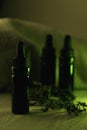 Vertical composition of three 10 ml black glass bottles surrounded with dried herbs