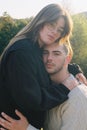 Vertical of a couple hugging each other and looking at the camera female standing higher