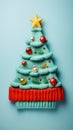 vertical creative 3D knitted Christmas tree made of threads, decorated with balls and toys on a plain background with