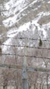 Vertical crop Focus on security chain link fence with barbed wires against on snowy hill slope Royalty Free Stock Photo