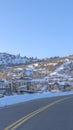 Vertical crop Road in Park City passing along snowed in mountain slopes with homes and trees