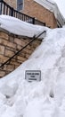 Vertical crop Snowed in stairs amid stone retaining wall with home and cloudy sky background