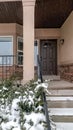 Vertical crop Snowy evergreens beside stairs that leads to porch of home with front bay window