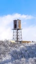 Vertical crop Water tank storage container on a tower at the snowy slope of Wasatch Mountains