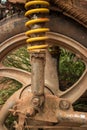 Vertical CU of muddy weathered grungy rear wheel and shock of light motorcycle in Asia