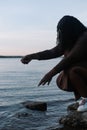 Vertical curly african afro american dark skin woman gently touching and splashing water in sea beach or river by hand. Royalty Free Stock Photo