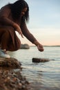 Vertical curly african afro american dark skin woman gently touching and splashing water in sea beach or river by hand. Royalty Free Stock Photo