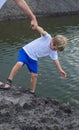 VERTICAL Dad helps son go down to lake water, explains safety rules. Evening. Happy childhood fatherhood. Family