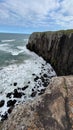 Vertical distant shot of high cliffs and a sea in Morro Da Guarita, Torres, Brazil