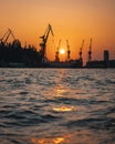 Vertical distant view of industrial cranes at the harbor with sunset in the background Royalty Free Stock Photo