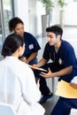 Vertical of diverse group of male and female doctors holding files sitting in discussion at hospital