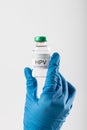 Vertical of doctor\'s gloved hand holding hpv vaccine vial on white background with copy space Royalty Free Stock Photo