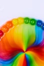 Vertical dome of skittles rainbow candy as sugar and water mix into a psychedelic hippie flower on a white background