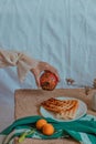 Vertical dreamy shot of hand holding a pomegranate over a table with tangerines and waffle