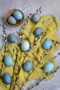 Vertical Easter composition. Gray marble eggs, yellow napkin and willow branches on a gray background. View from above