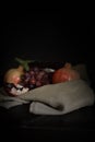 Vertical eggplant and pomegranate still life with grape on sackcloth dark lighting Royalty Free Stock Photo