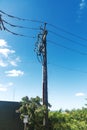 Vertical electric transmission tower standing on roadside with visible power cables and bright sky Royalty Free Stock Photo