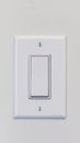 Vertical Electrical rocker light switch with flat broad lever on white interior wall