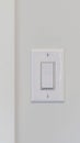 Vertical Electrical rocker light switch on white wall against blurry door background