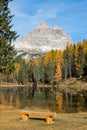 VERTICAL: Empty wooden bench faces the breathtaking Lago d\'Antorno and Dolomites