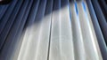 Vertical fabric white blinds on the window with light and shadow from the sun. Background and texture. Abstract pattern Royalty Free Stock Photo