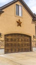 Vertical Facade of beautiful house with two brown wooden garage doors against cloudy sky