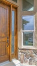 Vertical Facade of a home with shiny brown wooden front door and sidelight