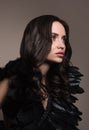 Vertical fashion portrait of young beautiful woman in black. Black hair and black feathers