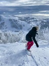 VERTICAL: Female snowboarder rides off piste overlooking empty ski resort slopes