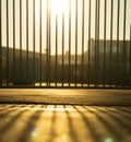 Vertical fence casting long shadows on pavement.. Royalty Free Stock Photo