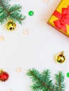 vertical festive background: two green branches, gold and red Christmas decorations, beads and a gift box with a bow. Copy Space Royalty Free Stock Photo