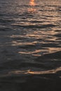 Vertical filled frame full screen desktop wallpaper shot of evening calm sea at dusk with orange sun reflection that makes the