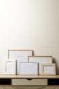 Vertical of five various empty frames with copy space on table against white wall