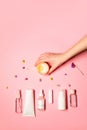 Vertical flat lay photo with beauty products: lipstick, serum, hand cream, toner, facial spray; and a hand holding a scented Royalty Free Stock Photo