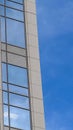 Vertical Focus on a modern building exterior with glass windows reflecting the blue sky Royalty Free Stock Photo