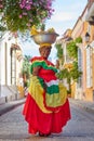Vertical footage of a Palenquera holding a big bowl of fruits on head, dressed with colorful clothes
