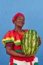 Vertical footage of a Palenquera holding a big heavy watermelon, dressed with colorful clothes